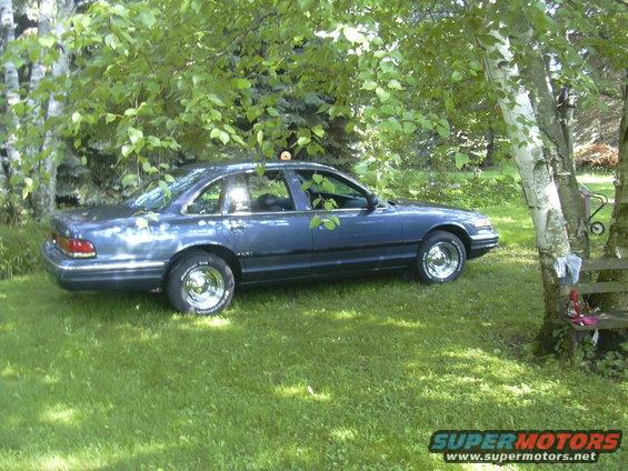 Blue 1996 Ford Crown Victoria parked on grass under trees