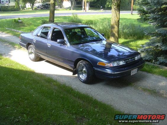1996 Ford Crown Victoria parked on a gravel driveway with grass and trees in the background