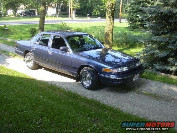 1996 Ford Crown Victoria parked on a gravel driveway with grass and trees in the background