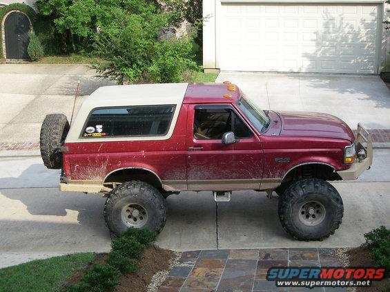 1995 Ford Bronco, red, lifted with large tires, parked in driveway