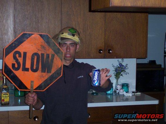 Guy in a hat holds a stop sign and a can of Bud Light in a kitchen
