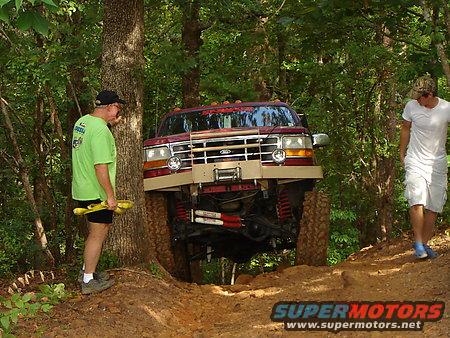 Red lifted truck with winch on off-road trail, two men nearby