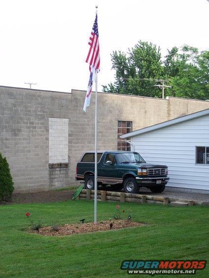 Green 1996 Ford Bronco parked in front of a white building with a flagpole and American flag