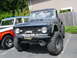 1973 Ford Bronco - A modified 1973 Ford Bronco with a winch and off-road tires is parked next to another Bronco.