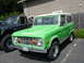 1973 Ford Bronco - A bright green 1973 Ford Bronco is parked next to another vehicle at an outdoor gathering.