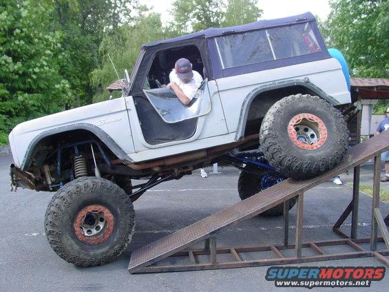 1973 Ford Bronco with lifted suspension and large tires on a metal ramp