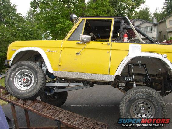 Yellow 1973 Ford Bronco with lifted suspension and off-road tires on a ramp