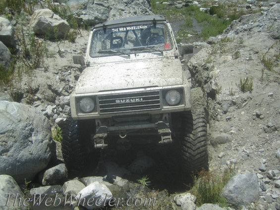 1987 Suzuki Samurai navigating a rocky, muddy trail