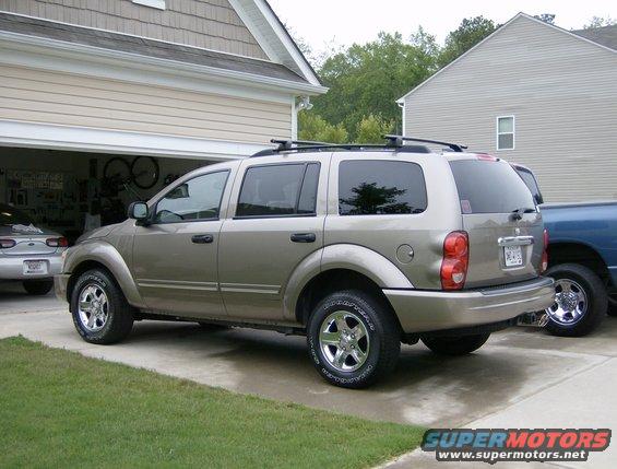 Tan 2004 Dodge Durango SUV parked in driveway, rear quarter view. Another vehicle is partially visible in the garage