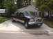 2004 Ford F-350 - This black dually pickup truck features a custom chrome grille and a "BOOMER" decal on the hood, consistent with a 2004 Ford F-350.