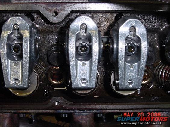 Close-up of engine valve train with three rocker arms visible. Part numbers F3TE-6529-AB are stamped on the rocker arms