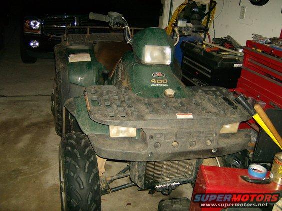 Green Polaris ATV with '400 Liquid Cooled' visible on the front, parked indoors