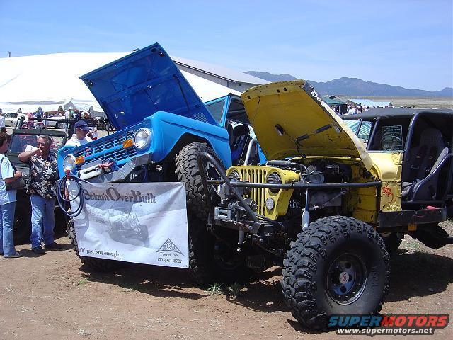 Blue 1986 Ford Bronco with hood open, parked next to a yellow Jeep