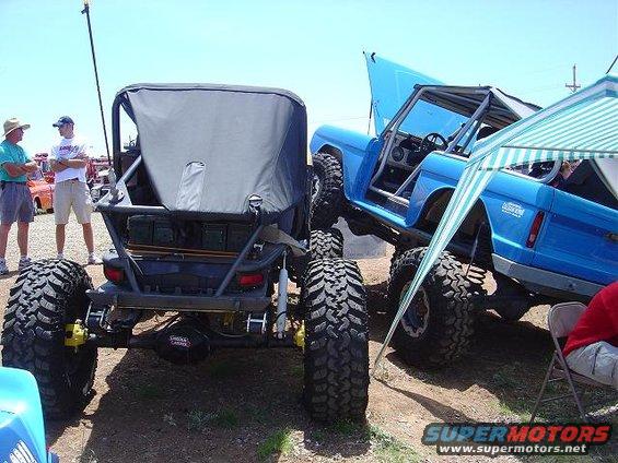Two heavily modified off-road vehicles, one blue with hood open, parked side-by-side