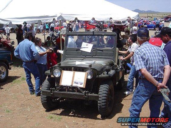 Military jeep with a star emblem on the hood, parked under a tent at an outdoor event