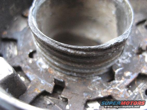 Close-up of a rusty metal hub with threaded interior and visible gear teeth