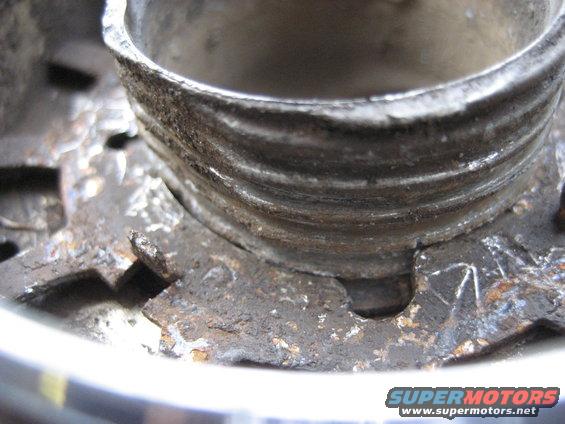 Close-up of a rusty Warn Premium hub with visible threads and mounting points. Supermotors.net logo visible at bottom right