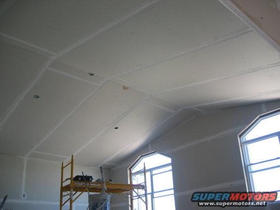 Scaffolding and drywall on a vaulted ceiling under construction, with arched windows
