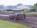 1994 Ford F-250 - A Jeep pickup truck navigates a muddy track with other vehicles and structures visible in the distance.