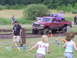 1994 Ford F-250 - A red pickup truck competes in a mud drag event, with a purple truck in the background.