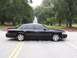 2001 Ford Crown Victoria - Side view of a black 2001 Ford Crown Victoria parked on a street with trees in the background.