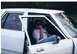 1987 Ford Crown Victoria LTD - A person sits inside a white sedan with the driver's door ajar.