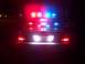 2003 Ford Crown Victoria - Rear view of a 2003 Ford Crown Victoria police car at night, with emergency lights flashing.