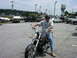 2006 Victory Kingpin - A man poses on a motorcycle in a dealership lot filled with various vehicles and boats.