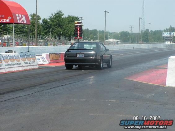 Dark hatchback Mustang on drag strip, rear view. License plate EXP 5080