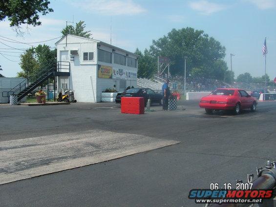 Red 1987 Ford Mustang on drag strip, rear view