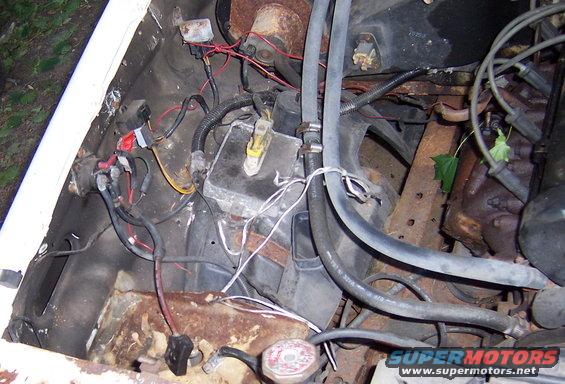 Engine bay with visible rust, wiring, hoses, and a SuperMotors logo