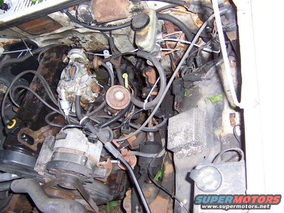 Engine bay showing carburetor, alternator, and various hoses and wires