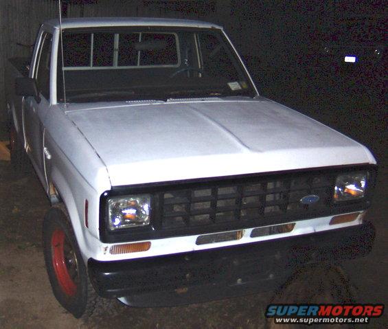Front view of a white pickup truck with a black grille and red-rimmed wheels