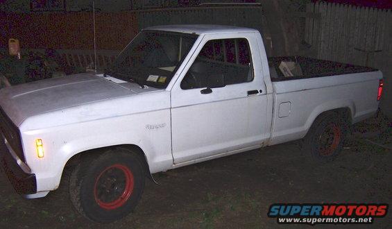 White pickup truck with red rims parked outside