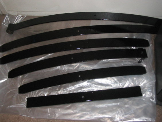 Black leaf springs laid out on plastic sheeting