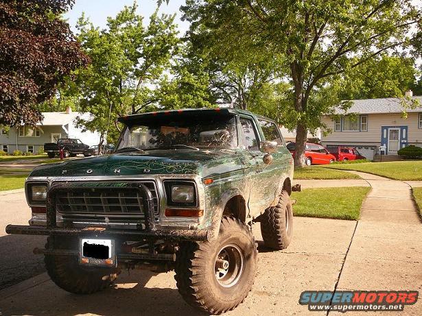 Green 1978 Ford Bronco with custom grille guard and large tires parked on a driveway