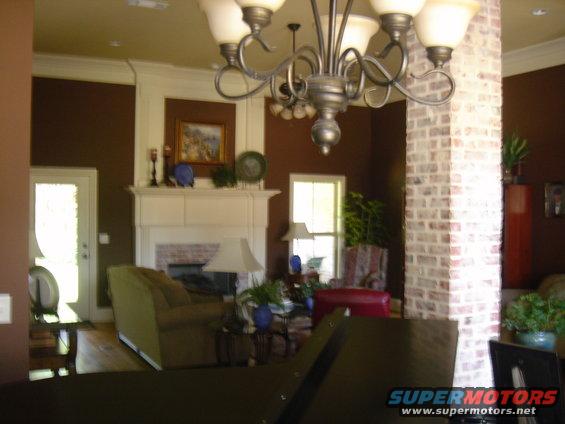Interior of a living room with a fireplace, chandelier, and brick column