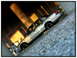 1998 Ford Crown Victoria - A silver 1998 Ford Crown Victoria is seen from the side, parked on a gravel slope beneath a concrete overpass.