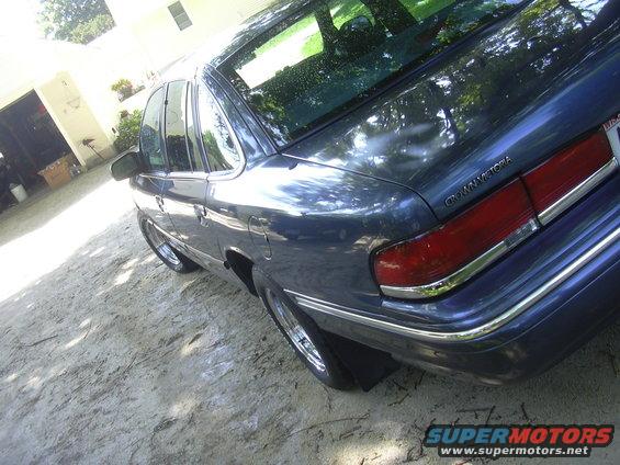 Dark blue Ford Crown Victoria parked on dirt lot. Rear quarter view shows taillight and chrome trim
