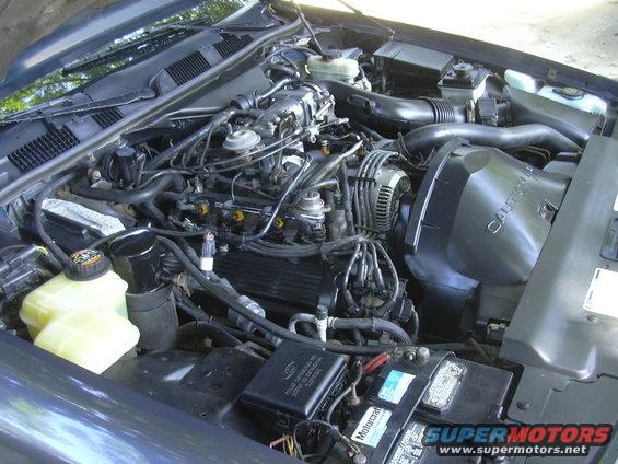 Engine bay with V8 engine, air intake, battery, and various hoses and wires