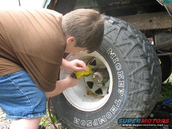 Person using a yellow tool on a Mickey Thompson tire