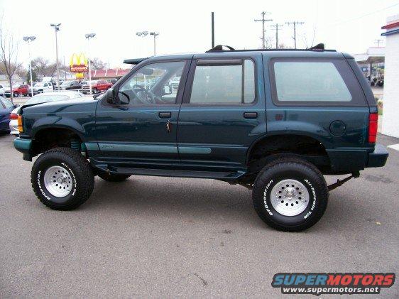 Dark green 1994 Ford Explorer lifted with off-road tires, side view