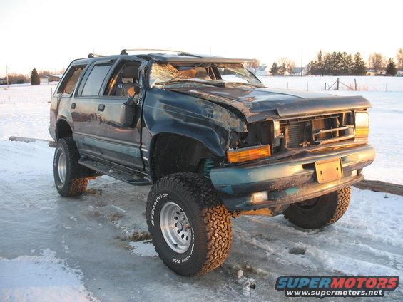 1994 Ford Explorer with significant front-end damage, lifted suspension, and off-road tires parked on icy ground