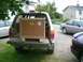 1995 Ford Probe - SUV is loaded with a large wooden crate, parked next to other vehicles in a residential area.