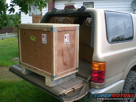 Gold SUV's open tailgate with a large wooden crate inside