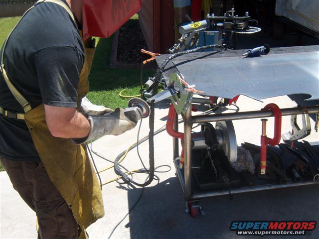 Welder grinding metal with a grinder, wearing protective gear