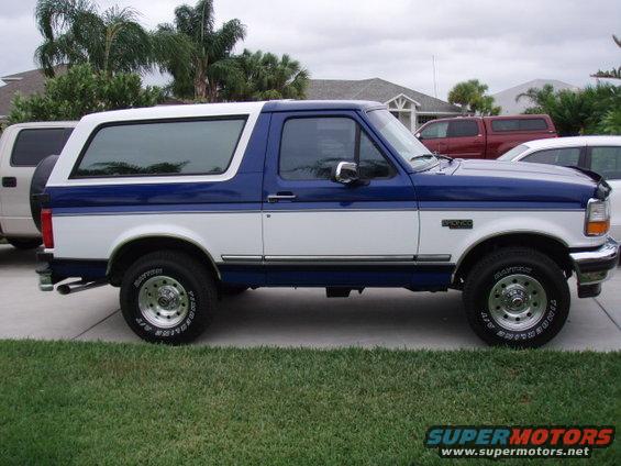Two-tone blue and white 1996 Ford Bronco, side view, with a spare tire mounted on the rear