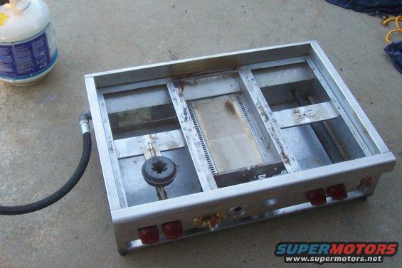 Propane camp stove with burner and hose connected to a propane tank
