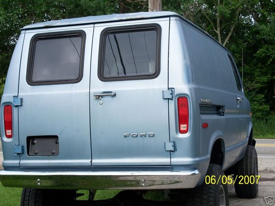 Rear view of a light blue 1978 Ford E250 van with chrome bumper and dual rear wheels