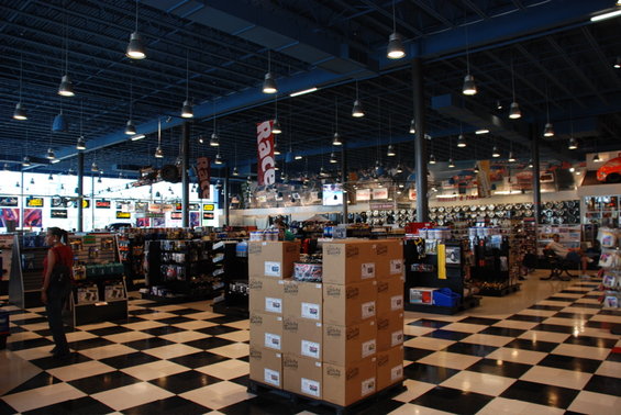 Interior of an auto parts store with checkered floors, shelves stocked with parts, and a banner that says "Race"